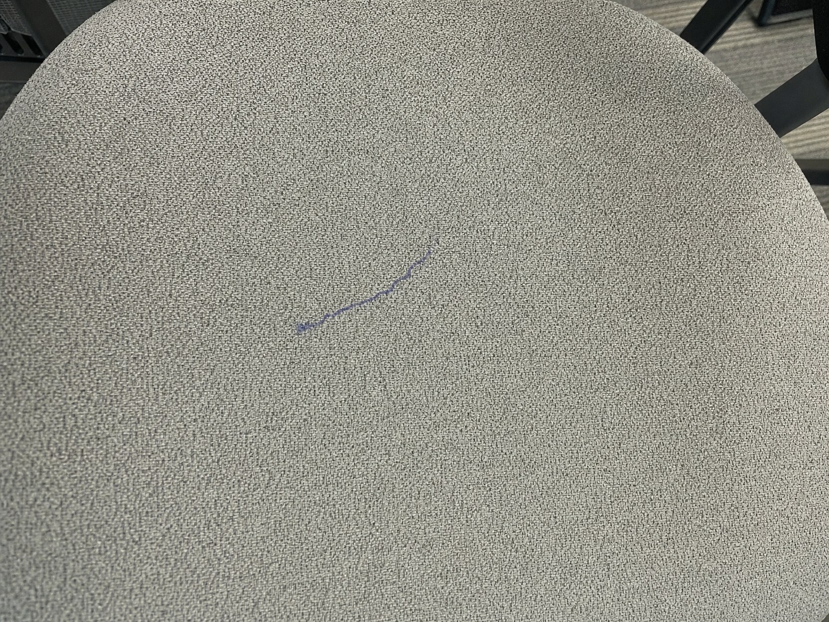 Linie de pix albastru pe tapițeria textilă gri a unui scaun de conferință, înainte de tratamentul cu Ink & Glue Remover PRO